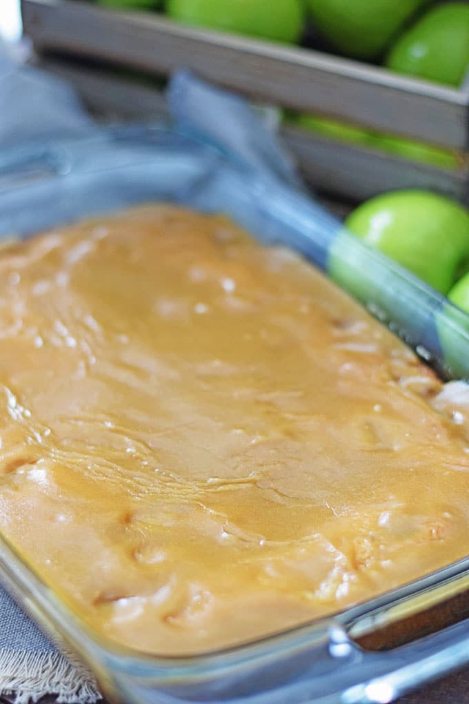 A clear glass baking dish with this fresh apple cake with a brown sugar glaze