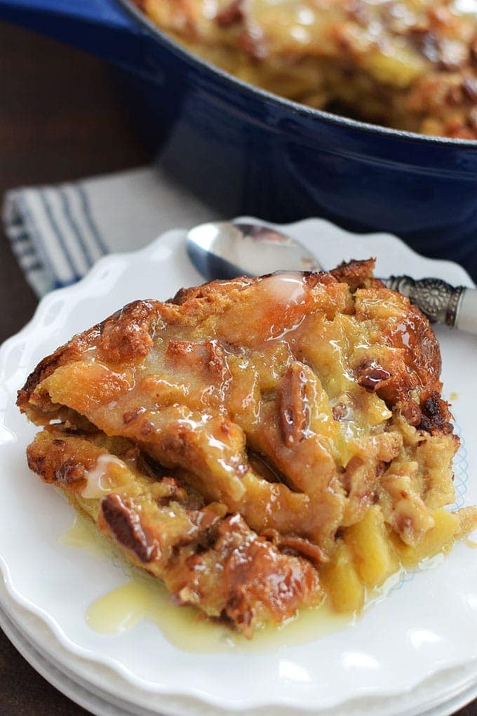 A slice of this bourbon apple pecan bread pudding on a white plate with a silver spoon