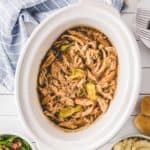 A white slow cooker filled with Mississippi Chicken