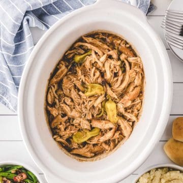 A white slow cooker filled with Mississippi Chicken