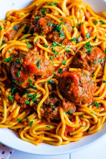 A close up of this Instant Pot spaghetti and meatballs with noodles, marinara sauce, and chopped basil