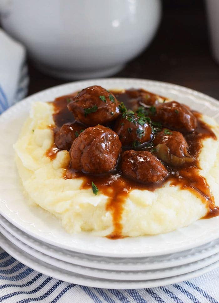 A white plate filled with mashed potatoes and these instant pot meatballs and gravy