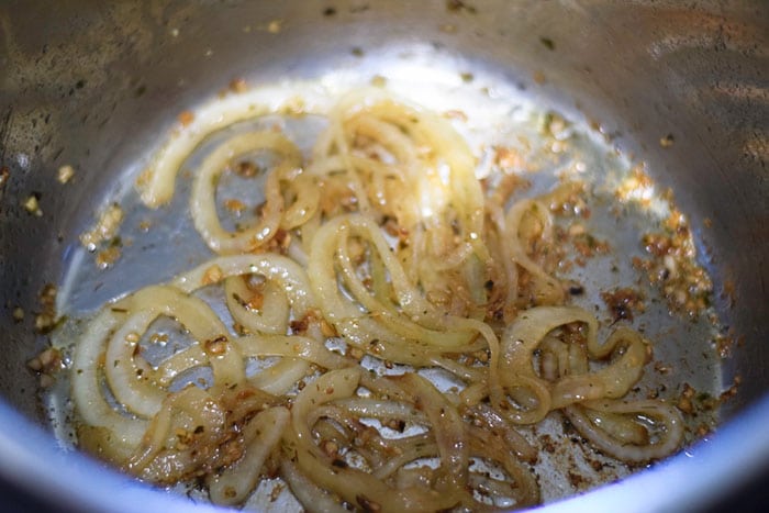 A closeup of browned onions in a skillet to be used in this instant pot meatballs and gravy recipe