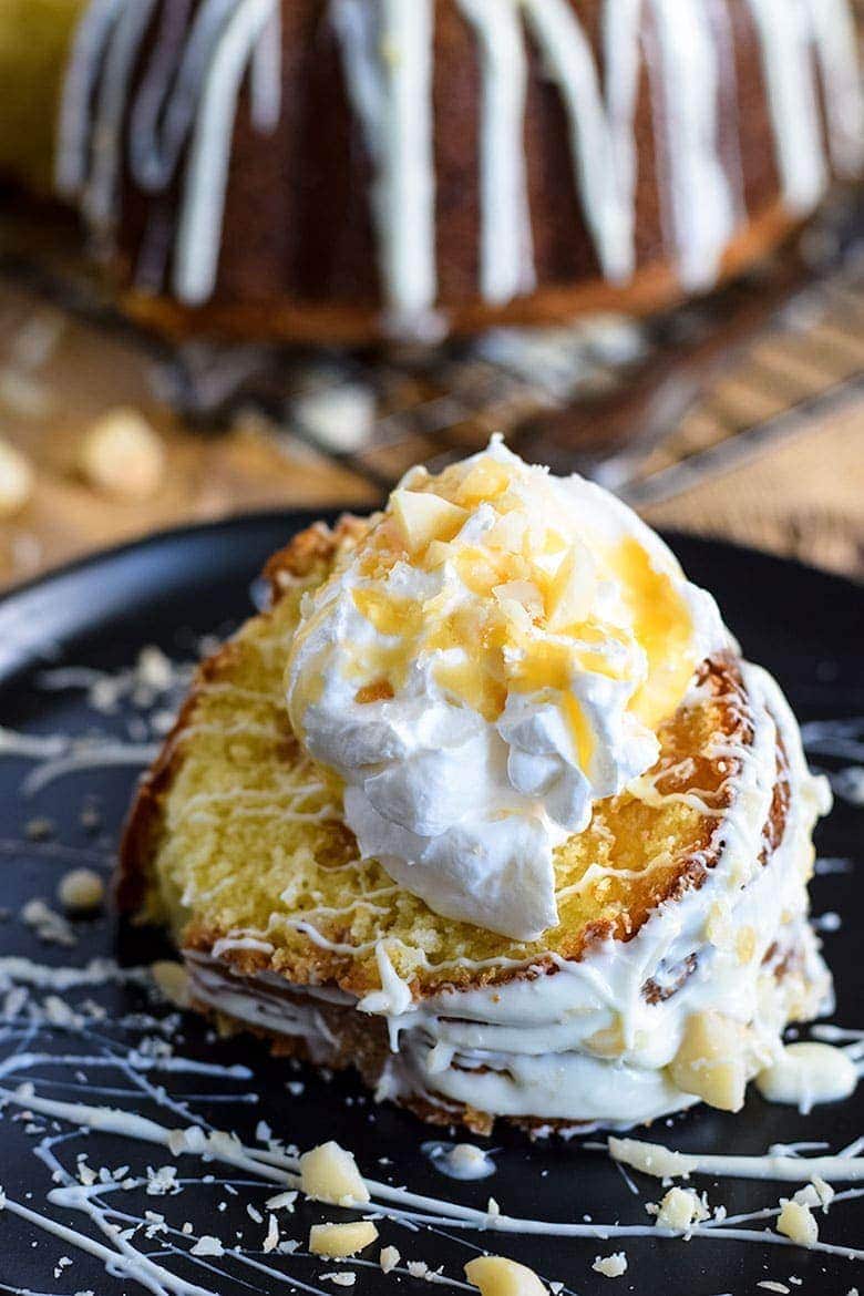 A slice of this white chocolate macadamia nut pound cake with icing, whipped cream, and shredded coconut