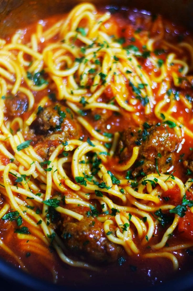 A close up of this Instant Pot spaghetti and meatballs with noodles, marinara sauce, and chopped basil