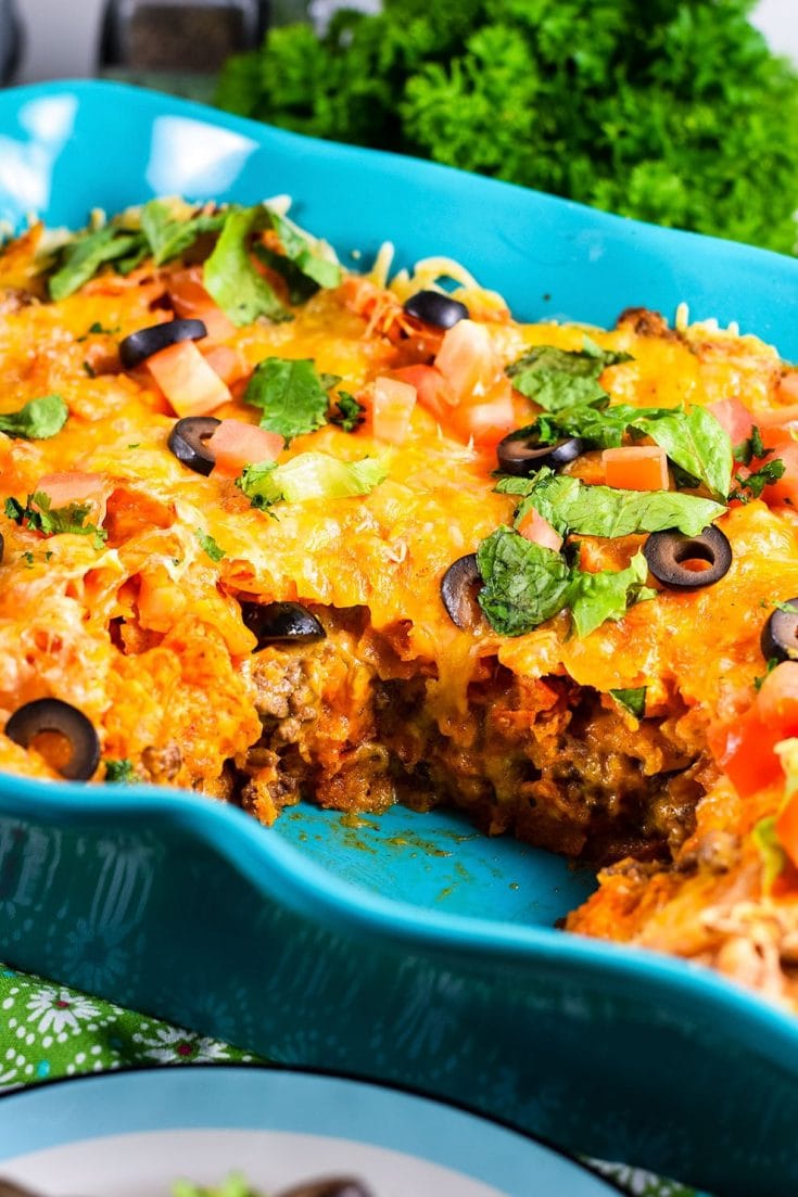 A closeup of this ground beef Doritos casserole with black olives, diced tomatoes, and parsley