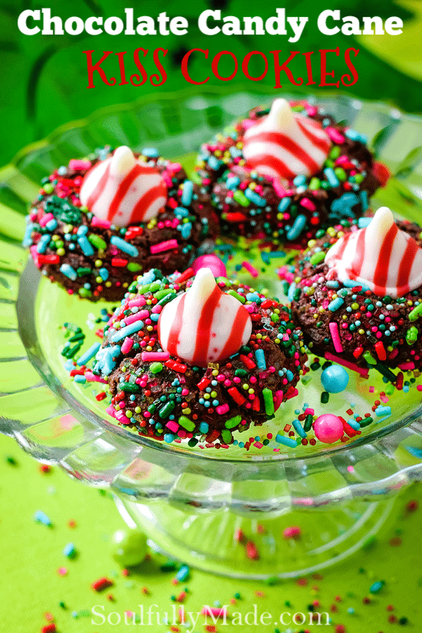Several chocolate candy cane Hershey\'s kiss cookies with Christmas sprinkles on a glass platter