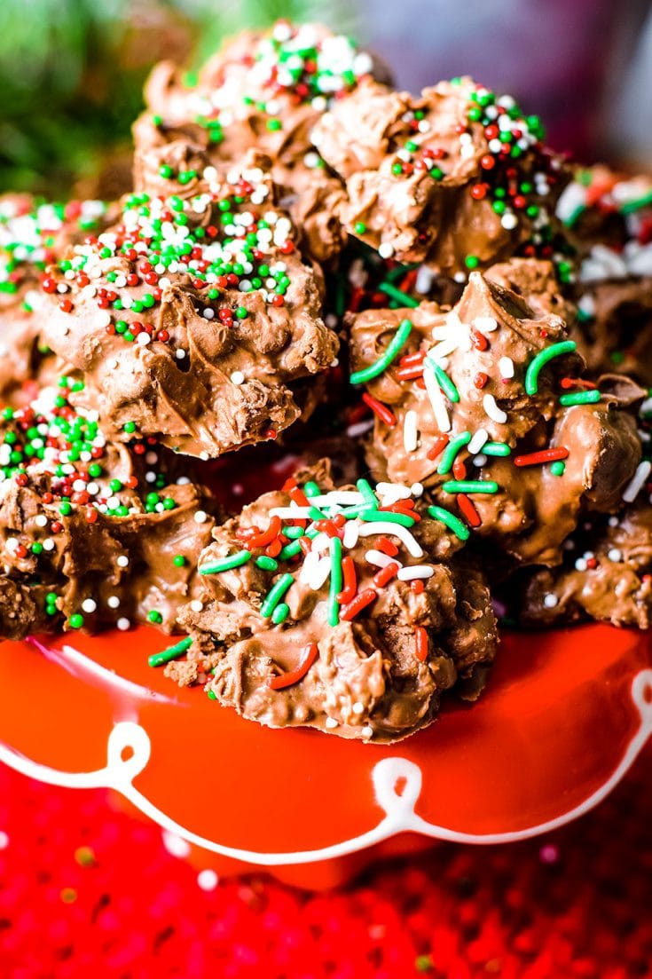 A close up of these homemade crock pot turtle candies garnished with red, white, and green sprinkles for Christmas