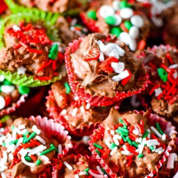 A close up of these homemade crock pot turtle candies garnished with red, white, and green sprinkles for Christmas