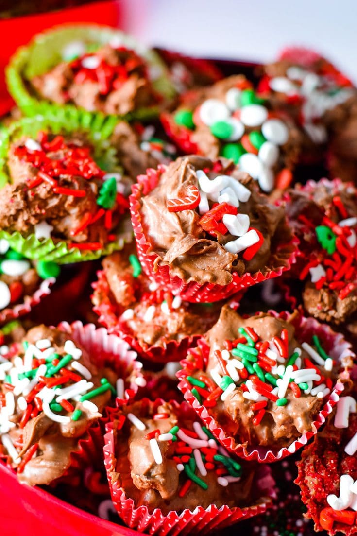 A close up of these homemade crock pot turtle candies garnished with red, white, and green sprinkles for Christmas