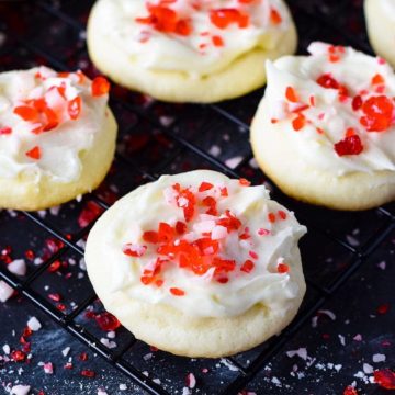 Four peppermint melt-away cookies with white chocolate icing and candy cane sprinkles