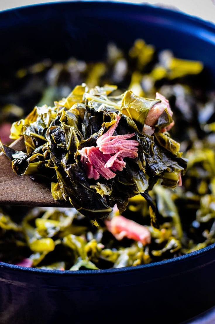 Wooden serving spoon scoop full of southern collard greens.