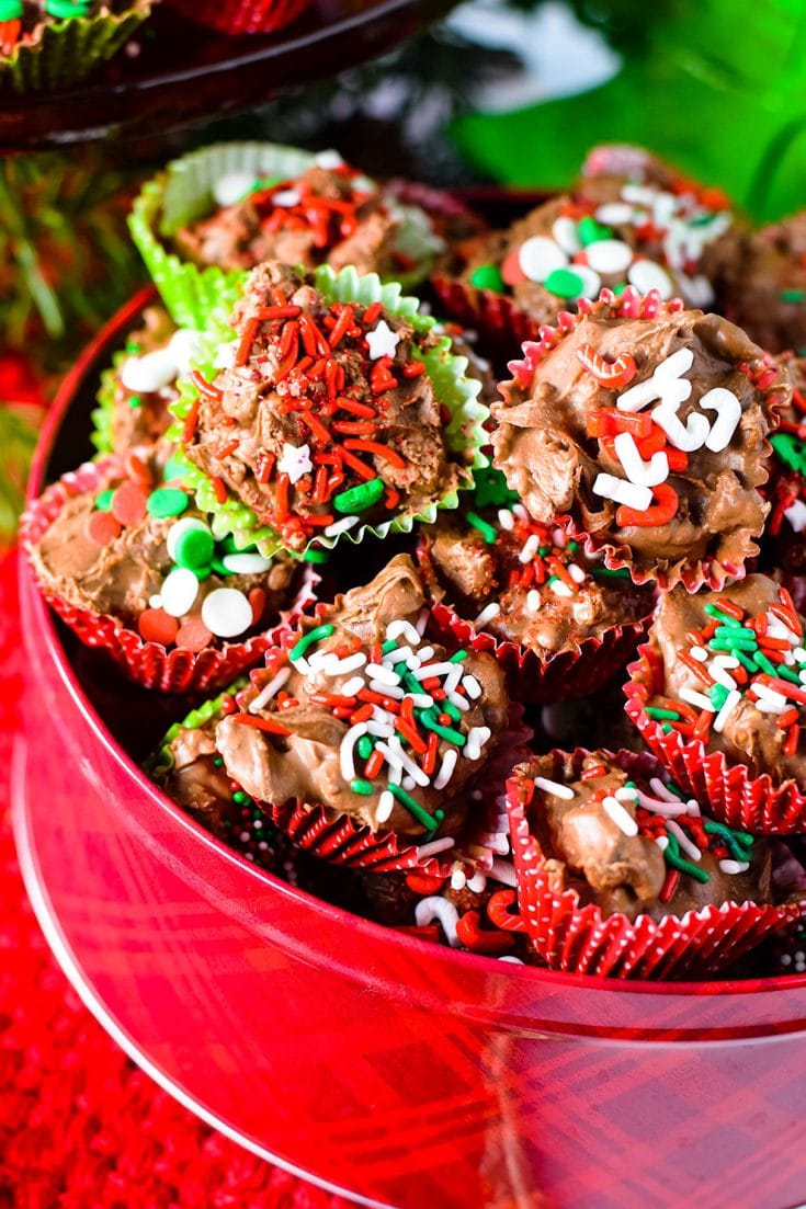 A close up of these homemade crock pot turtle candies garnished with red, white, and green sprinkles for Christmas