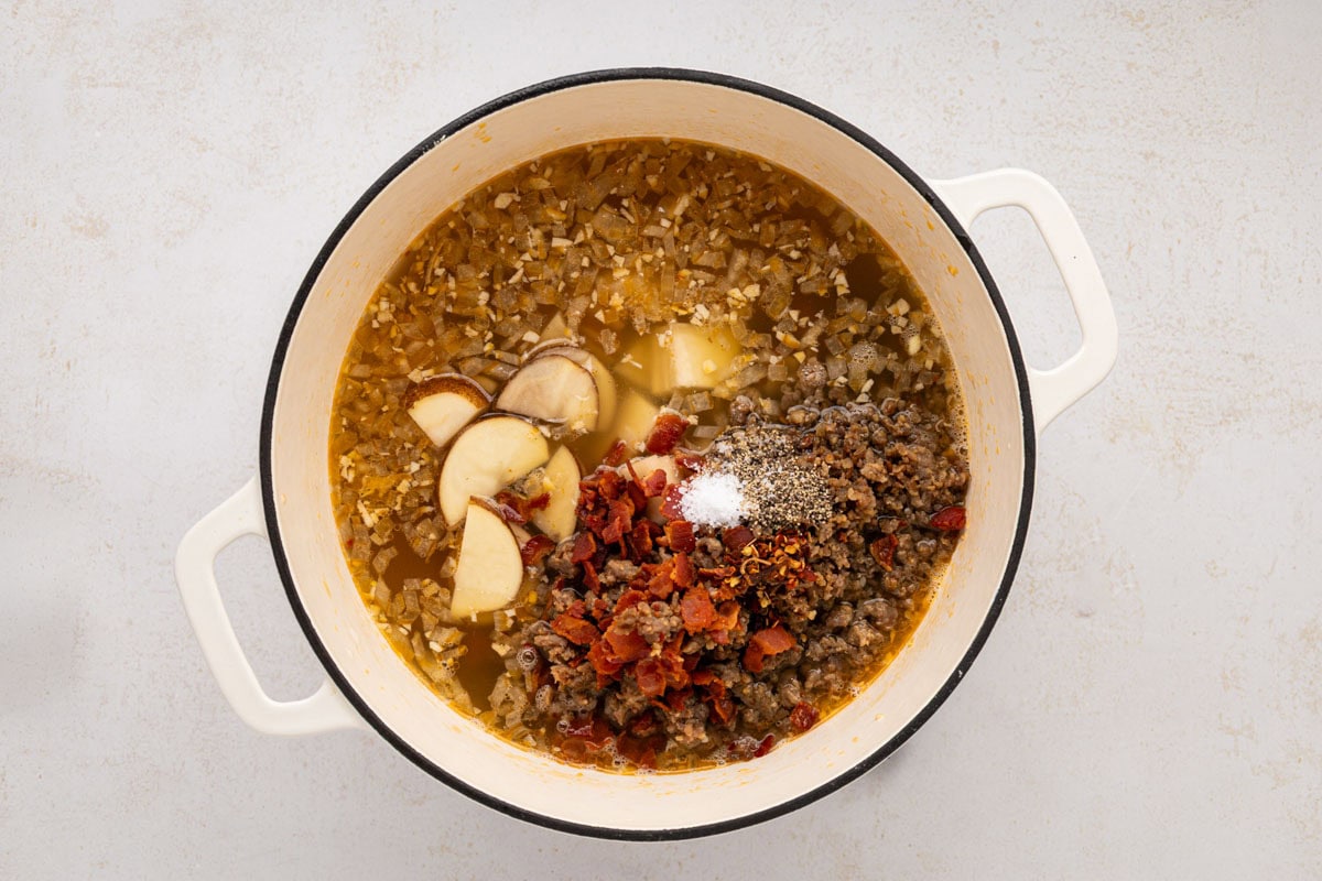 Meats, potatoes and spices added to the soup pot.