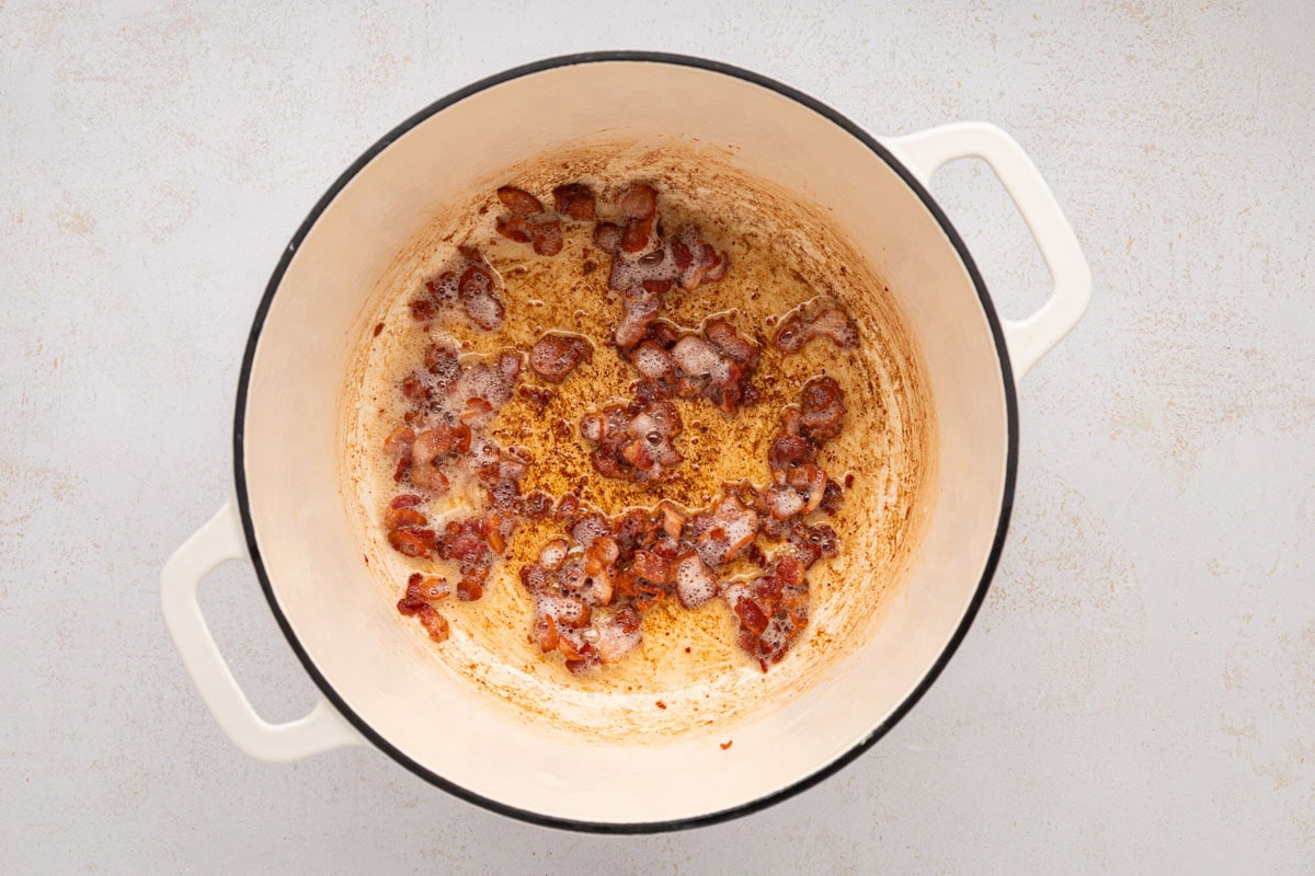 Cut bacon pieces cooking in a dutch oven.