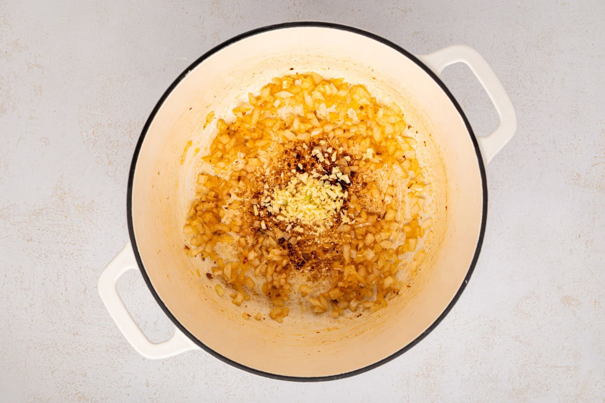 Garlic added to onion and grease in a dutch oven.