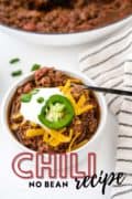 No bean Chili Recipe in a bowl topped with cheese, sour cream and a jalapeno.