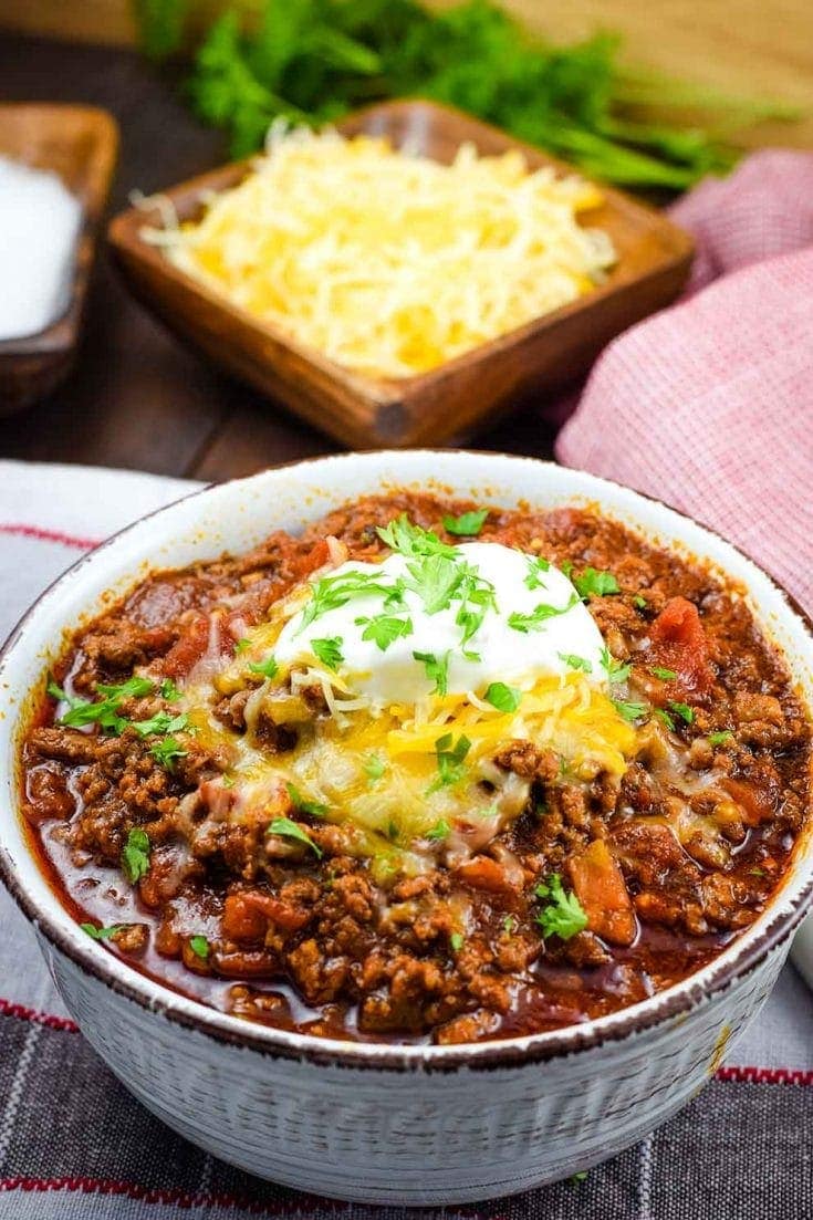 A bowl of this low-carb no-bean chili recipe topped with shredded cheese, sour cream, and parsley