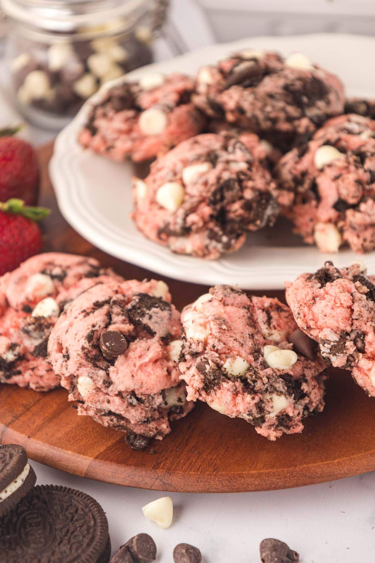 Strawberry cheesecake Oreo cake mix cookies on a wooden board with strawberries.