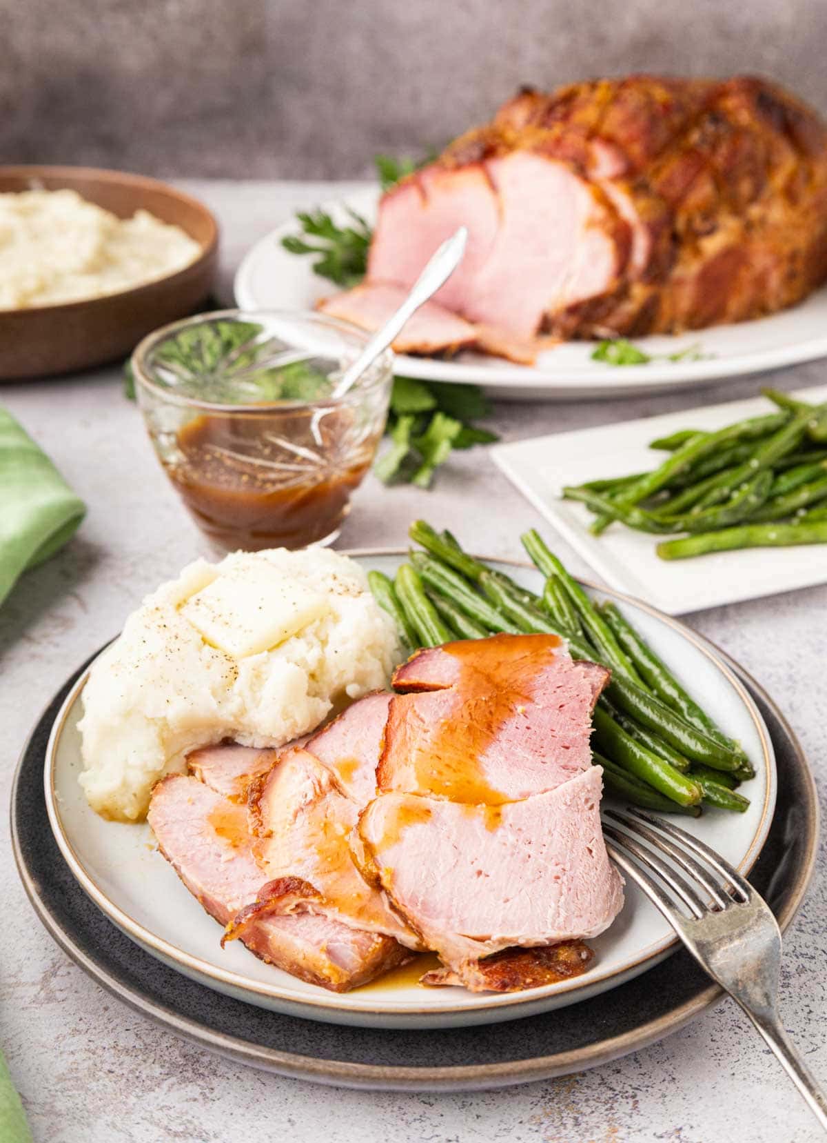 Sliced ham on a plate with mashed potatoes and green beans