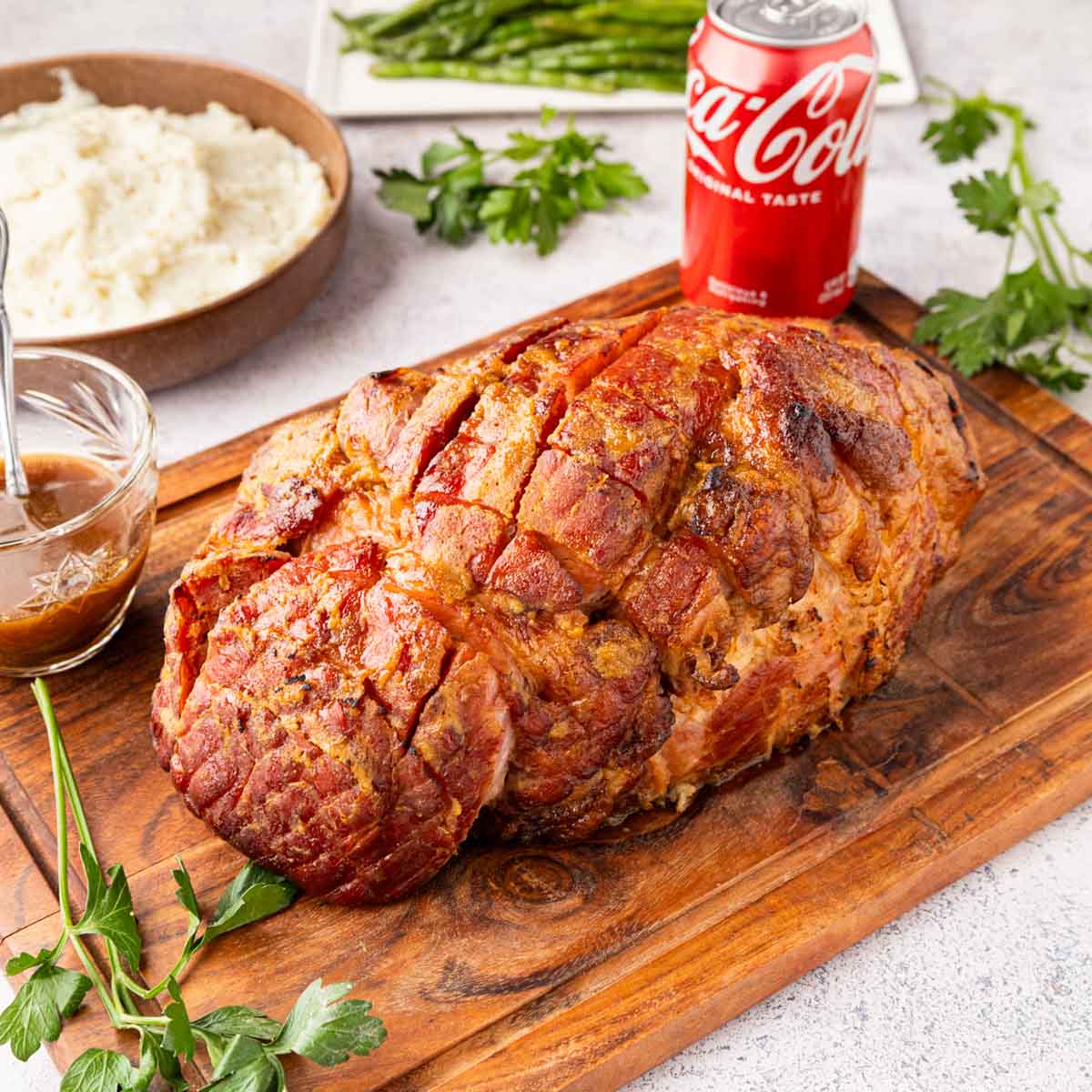 A Coca-Cola brown sugar and mustard glazed ham on a cutting board.