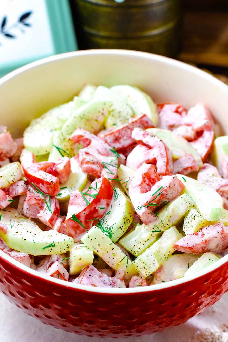 A large bowl filled with creamy cucumber and tomato salad
