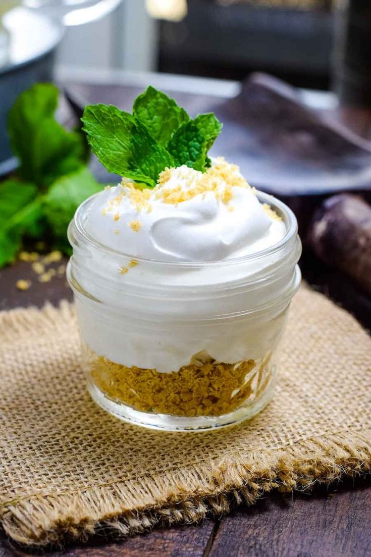 Key Lime Pie in a Mason Jar Topped with whipped cream and garnished with mint leaves.