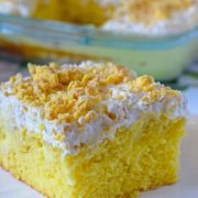 A slice of lemon cake topped with whipped icing on a white plate.