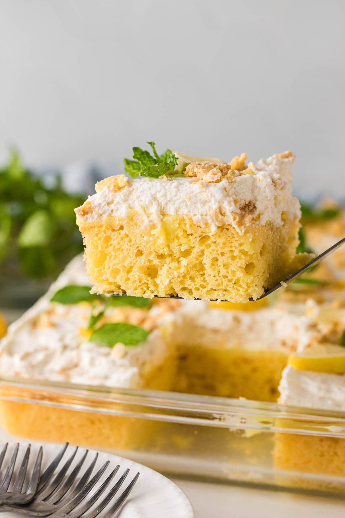 A slice of lemon pudding poke cake being removed from the baking dish with a serving spatula.