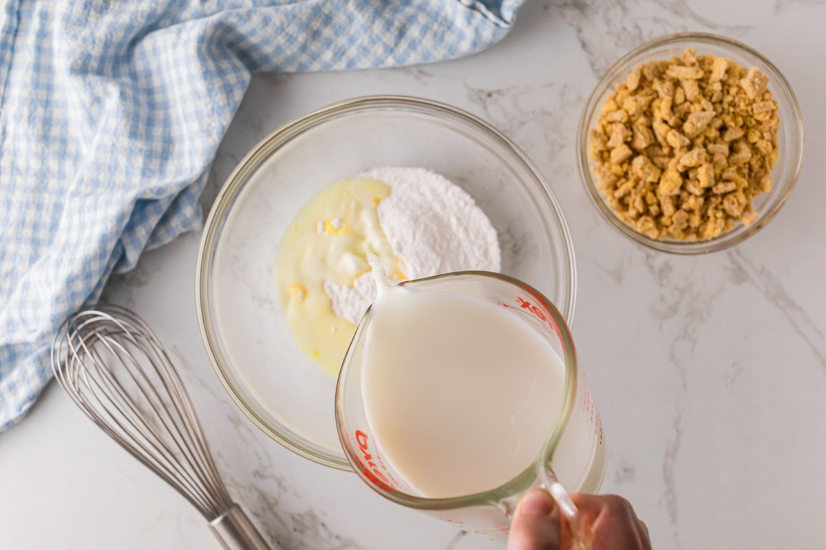 Pouring cold milk into instant lemon pudding mix.