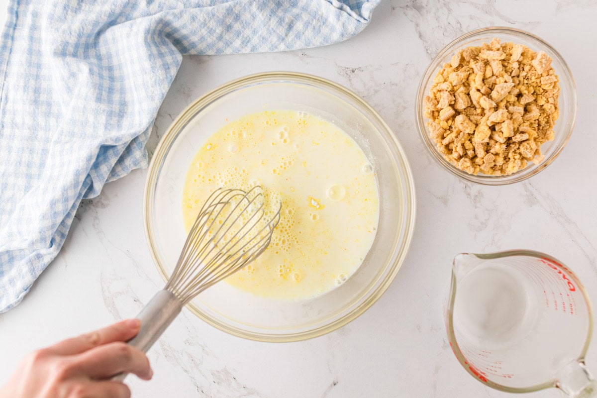 Whisking lemon pudding together in a bowl.