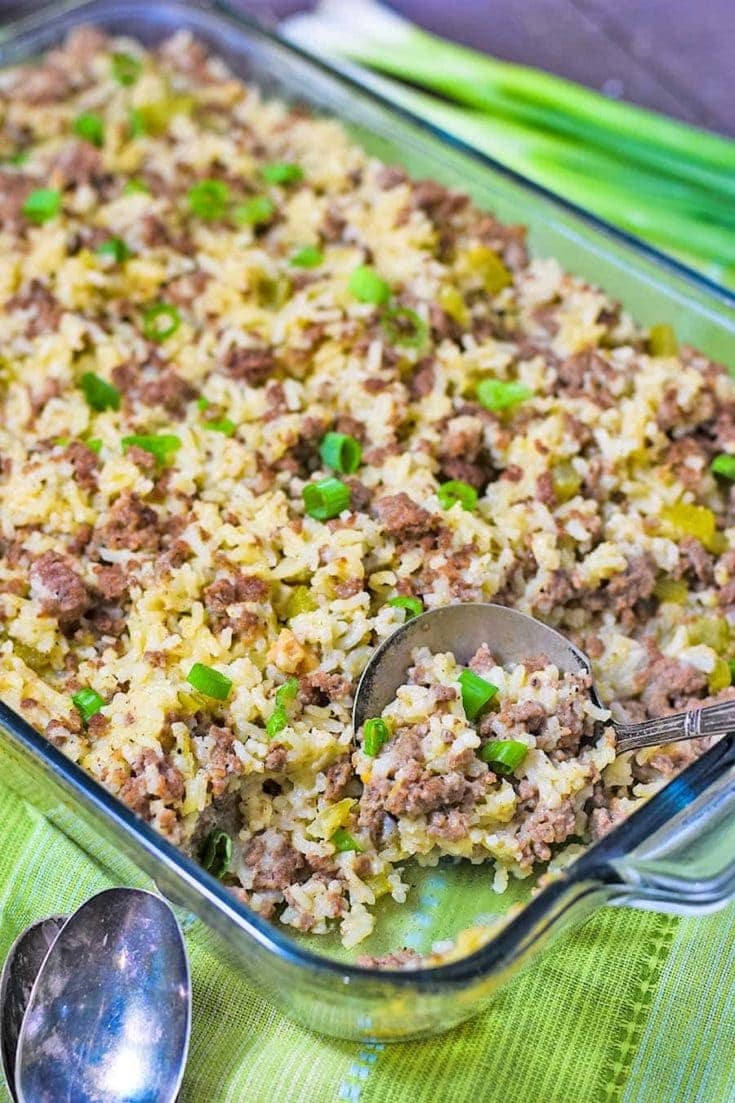 a casserole dish filled with ground beef and sausage casserole with a serving spoon