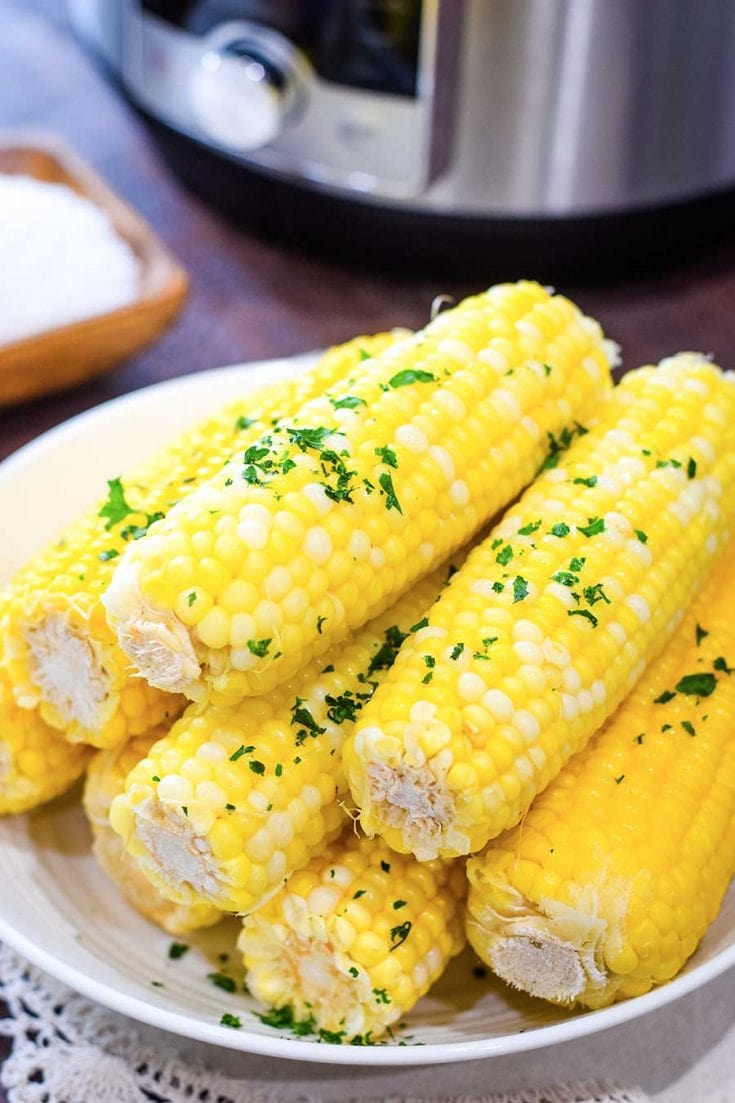 Instant Pot Corn on Cob on a white plate with drizzled butter and parsley