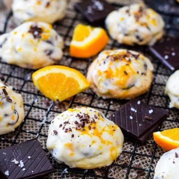 Salted dark chocolate cookies on a cooling rack with sliced oranges and chocolate garnish.