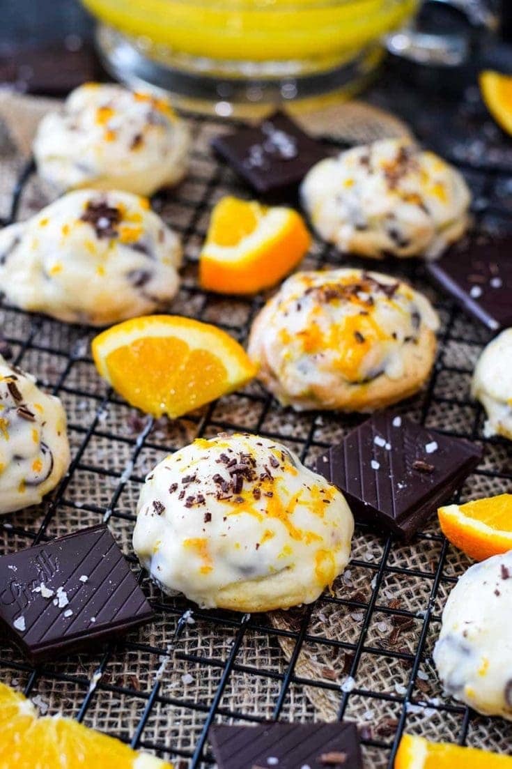 Salted dark chocolate cookies on a cooling rack with sliced oranges and chocolate garnish.