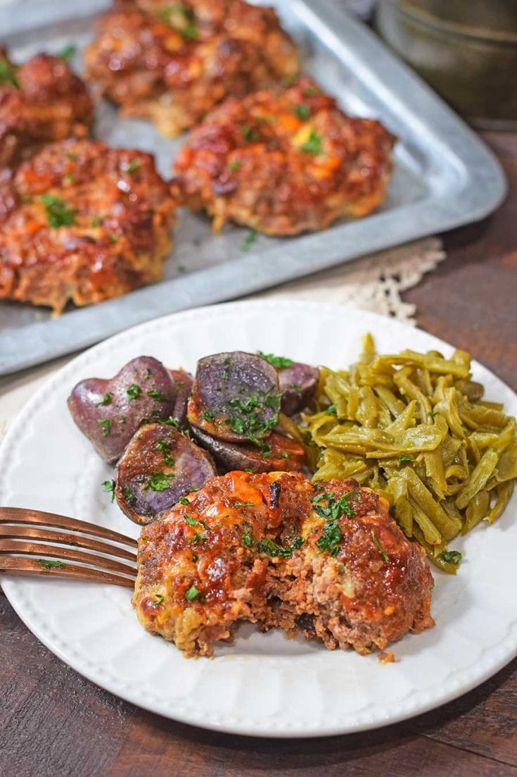 A plate of food on a table, with meatloaf, green beans, and purple potatoes.