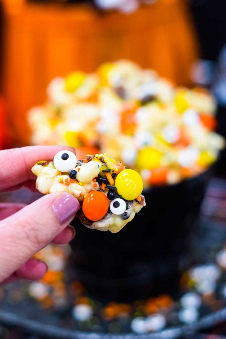 A close-up of a person holding food, with Popcorn and Candy.