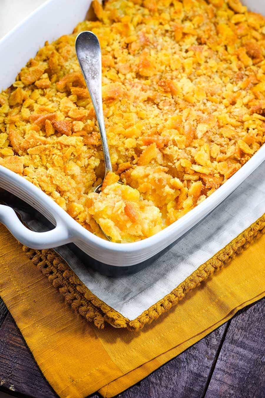 Pineapple casserole on a golden placemat set on a wooden table. 