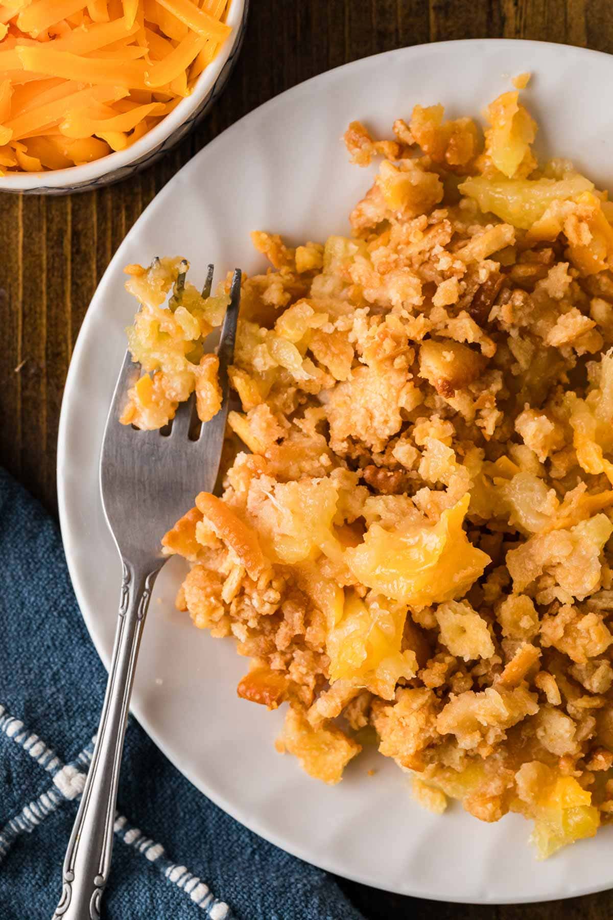 A fork with a bit of the pineapple and cheese casserole set on the plate with an up close view of the serving.