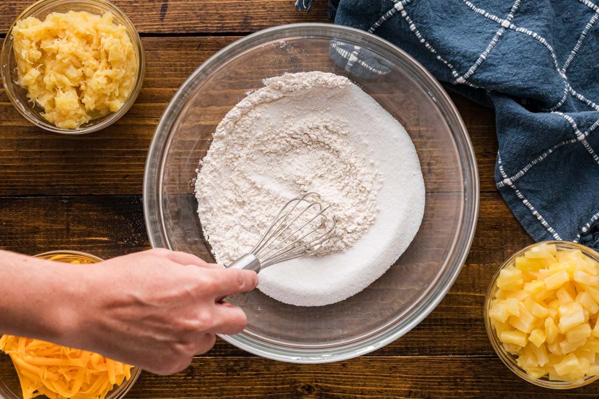 Using a whisk to combine flour and sugar in a bowl.
