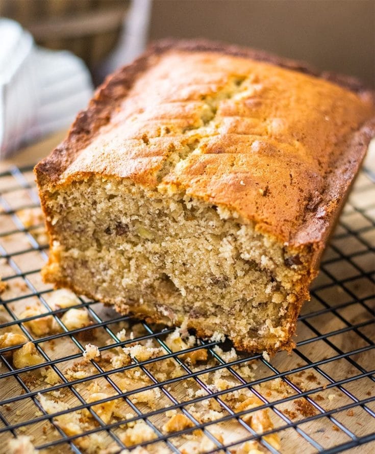 A half loaf of banana bread on a cooling rack.