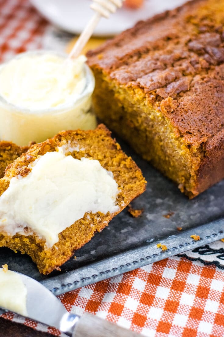 A slice of the Best Pumpkin Bread Recipe with a schmear of softened honey butter