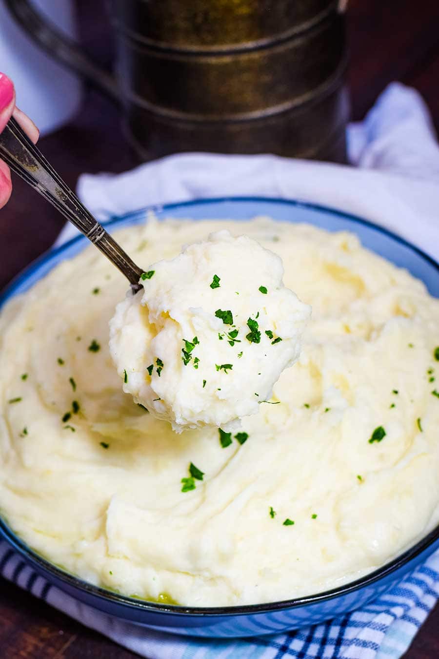 A bowl of slow cooker mashed potatoes served with a spoon.