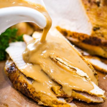 a white gravy boat pouring gravy on this sliced instant pot turkey breast