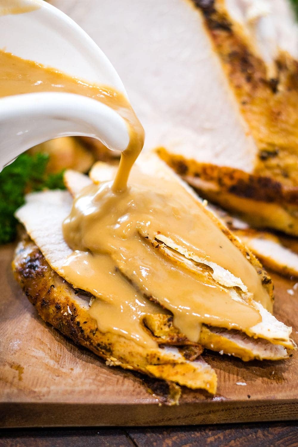 a white gravy boat pouring gravy on this sliced instant pot turkey breast
