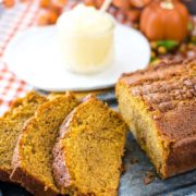 A close up of the Best Pumpkin Bread Recipe in both slices and as a loaf with softened butter in the background