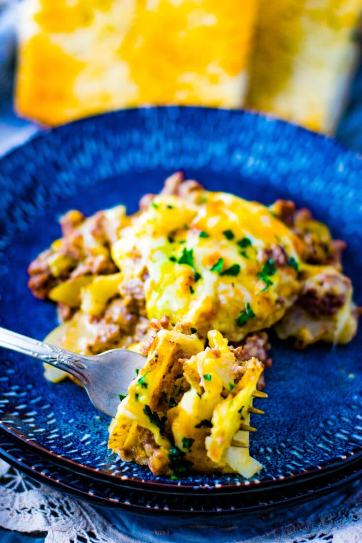 A single serving of this Easy Ground Beef and Potatoes Skillet on a dark blue plate with a fork