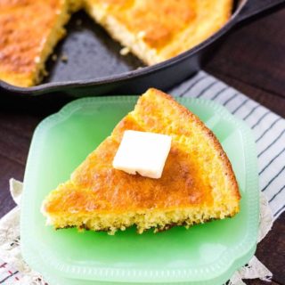 A piece of cornbread sitting on a green plate.