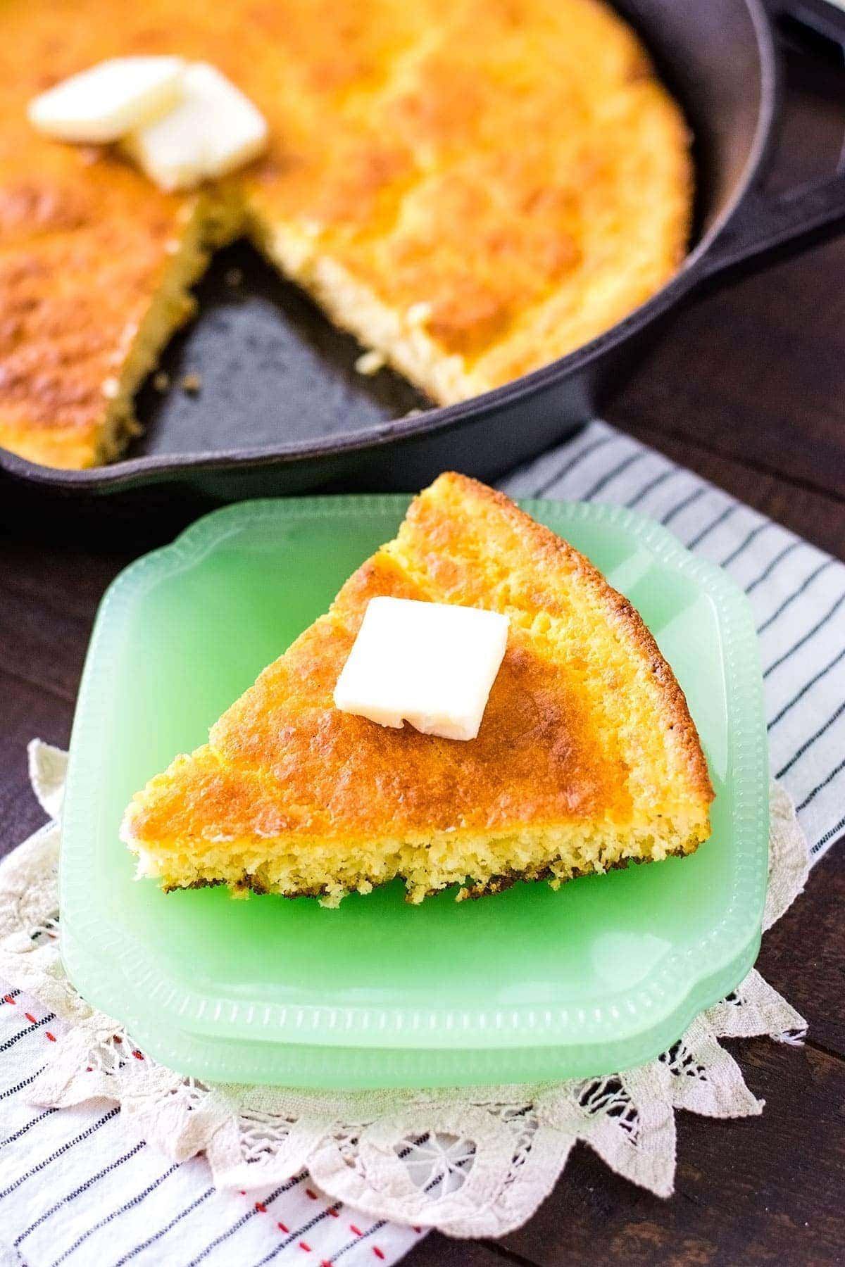 A piece of cornbread sitting on a green plate.