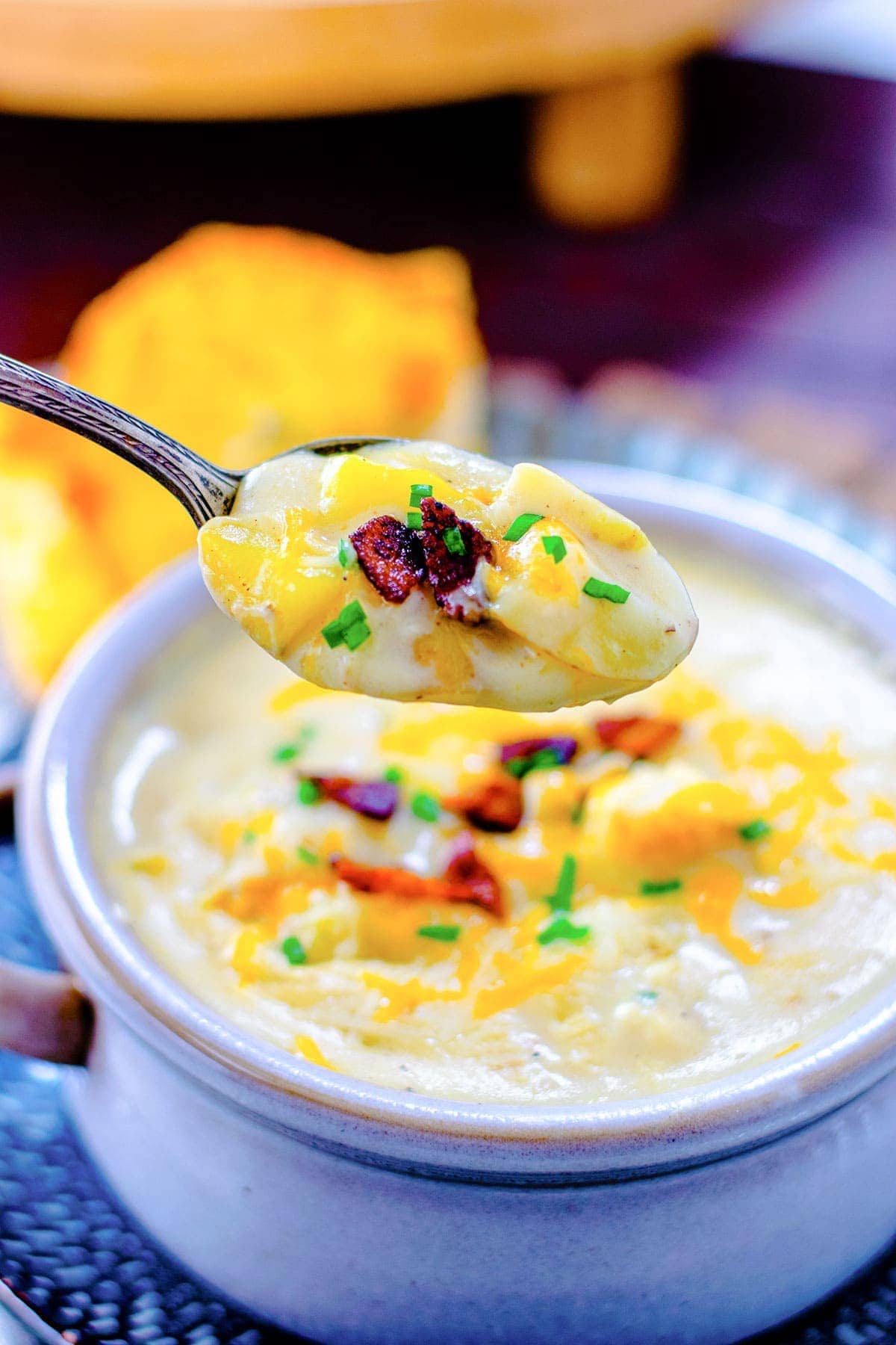 A bowl of potato soup with an up close spoon full being dipped out. 